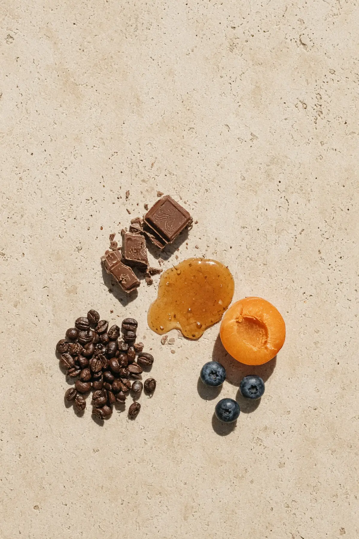 Milk chocolate, ripe fruit and caramel beside coffee beans on stone
