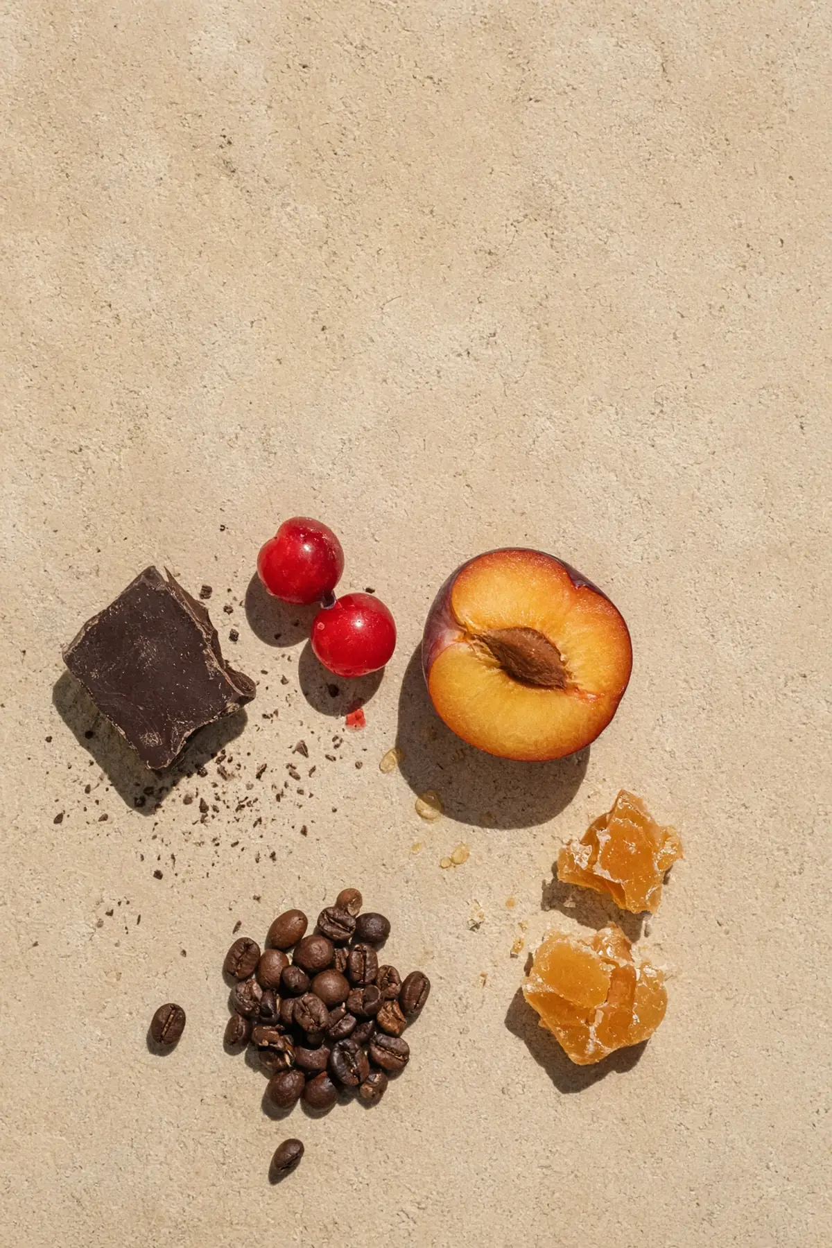Dark chocolate, red fruit and butterscotch beside coffee beans on stone